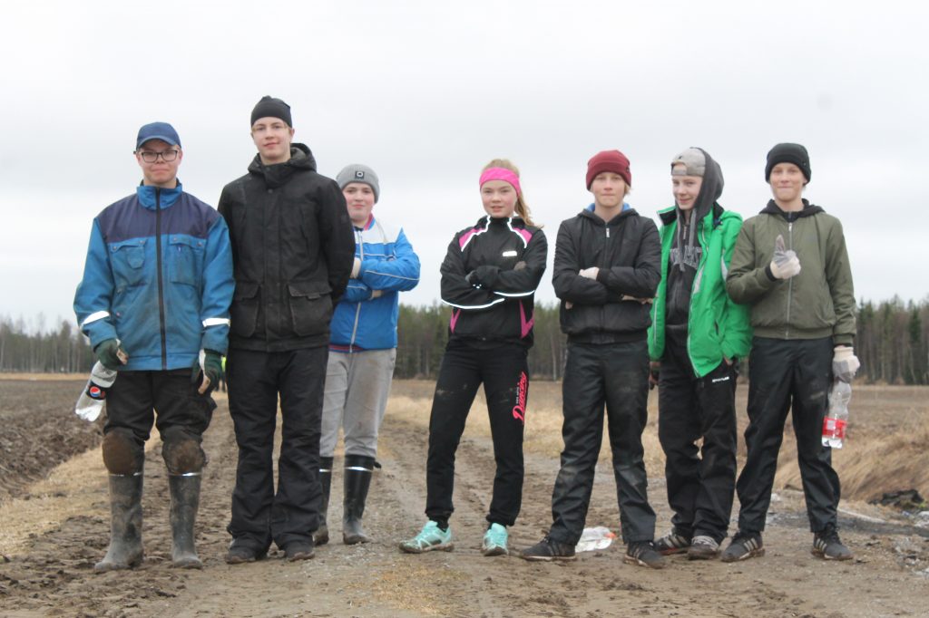 Kuva nuorista perunan istuttajista seisomassa maantien reunalla.