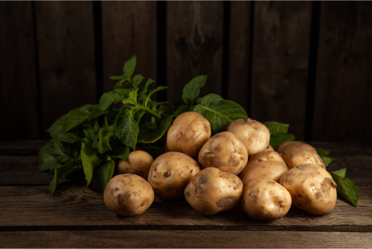 Perunoita ja lehtiä puupöydällä.