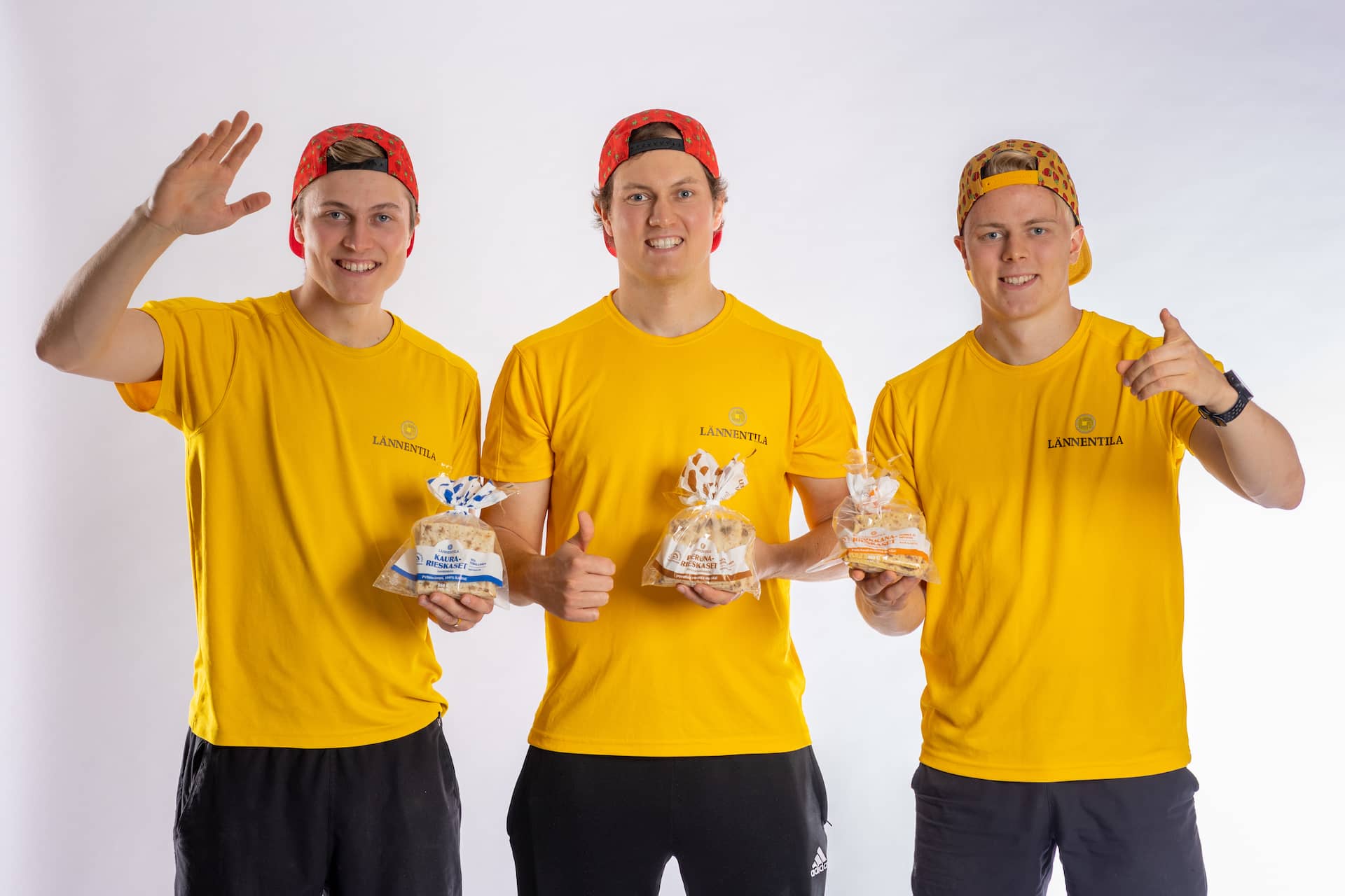 Lännentilan veljekset keltaisissa paidoissa pitämässä ruokaa käsissään ja hymyilemässä.